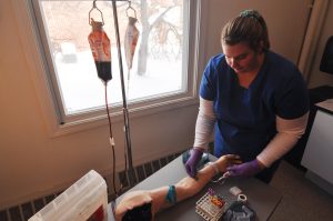 Phlebotomy student practices drawing blood.