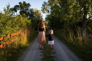 A woman and child walk down a wooded path.